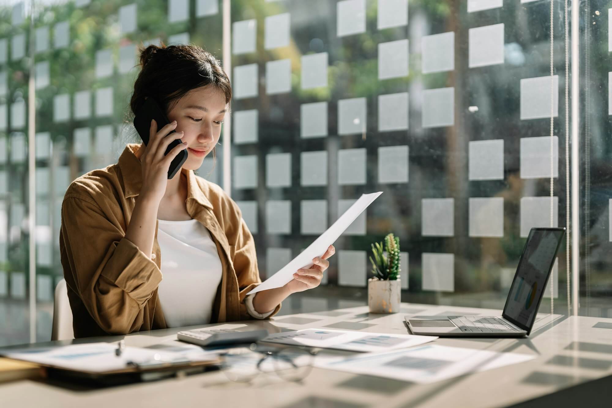 young-asian-accountant-calling-marketing-consultants-and-using-laptop-computer-to-analyze-sales.jpg